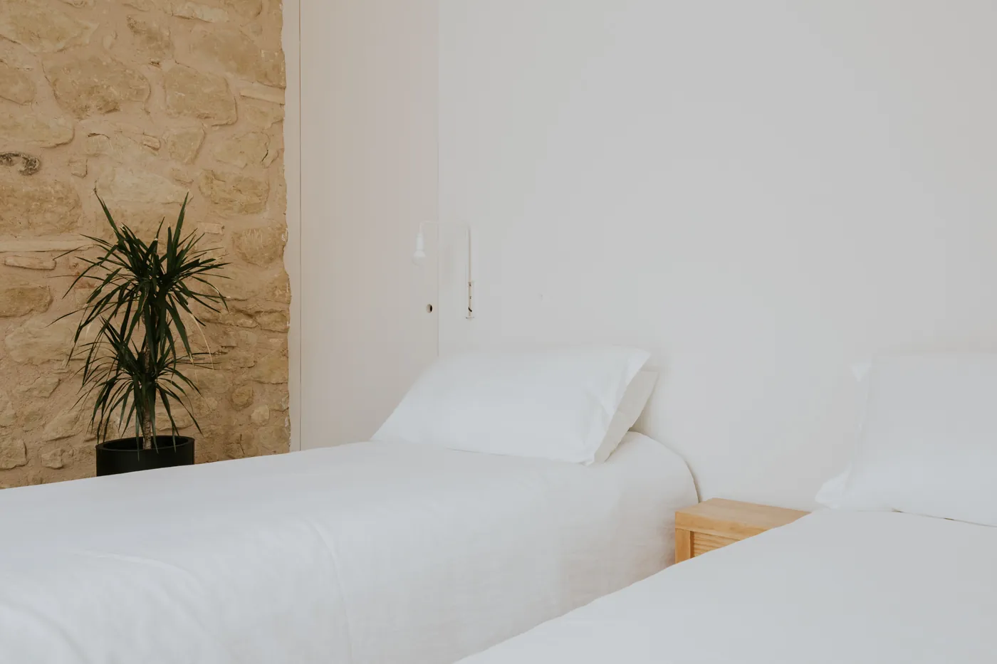 Habitación con dos camas individuales junto a una pared de piedra