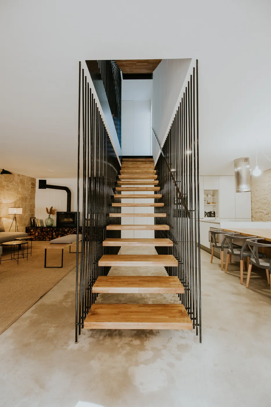 Vista frontal de la escalera flotante, con el salón a un lado y la cocina al otro
