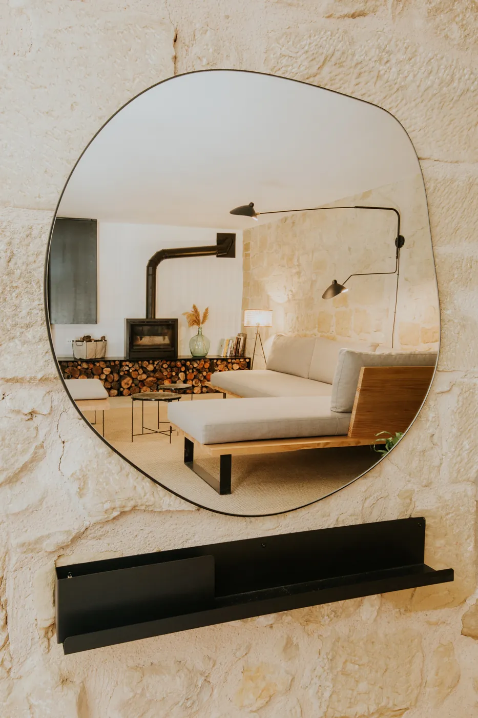 Un espejo de pared refleja el salón con la chimenea encendida y el sofá