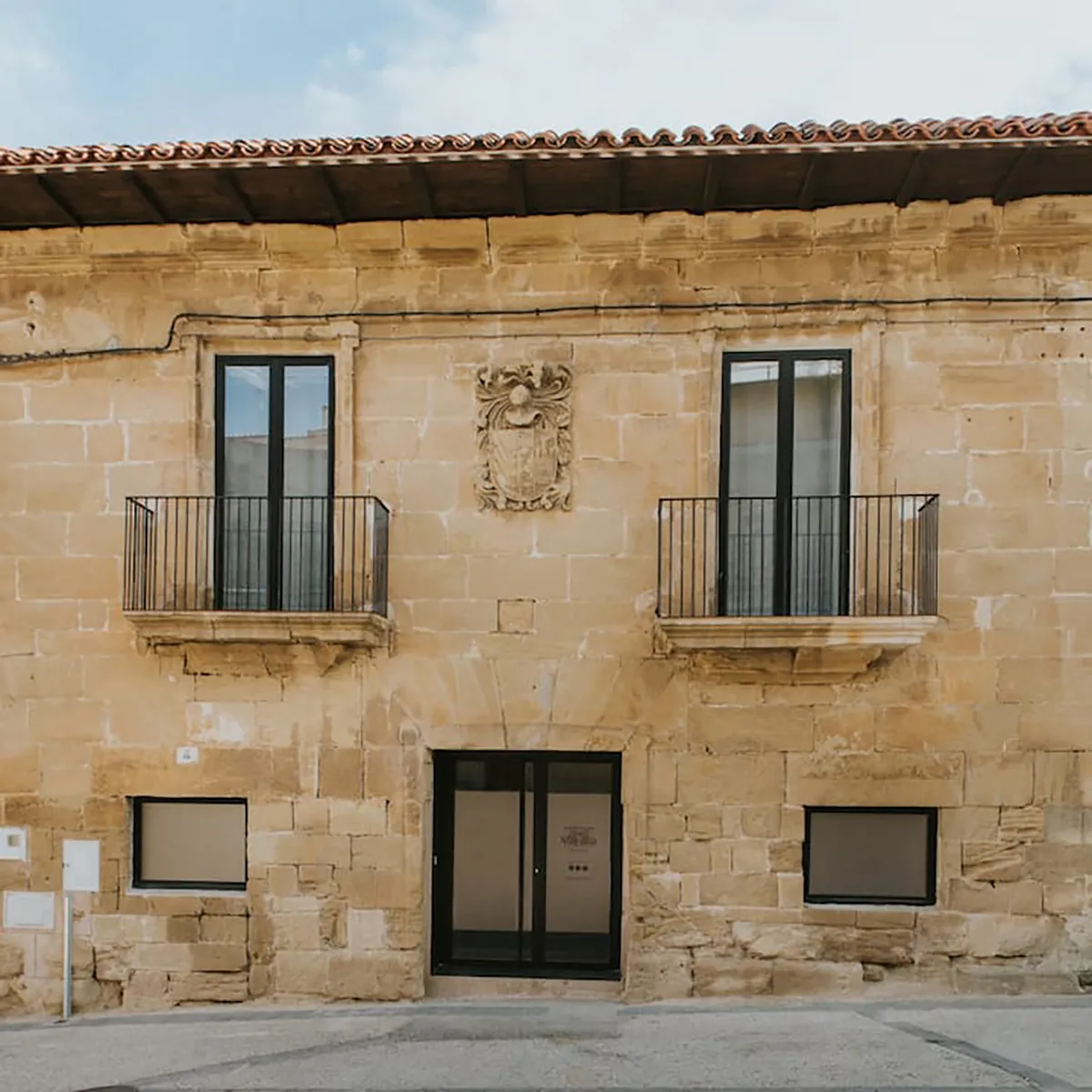 Fachada de piedra de La Macana con dos balcones y un escudo heráldico