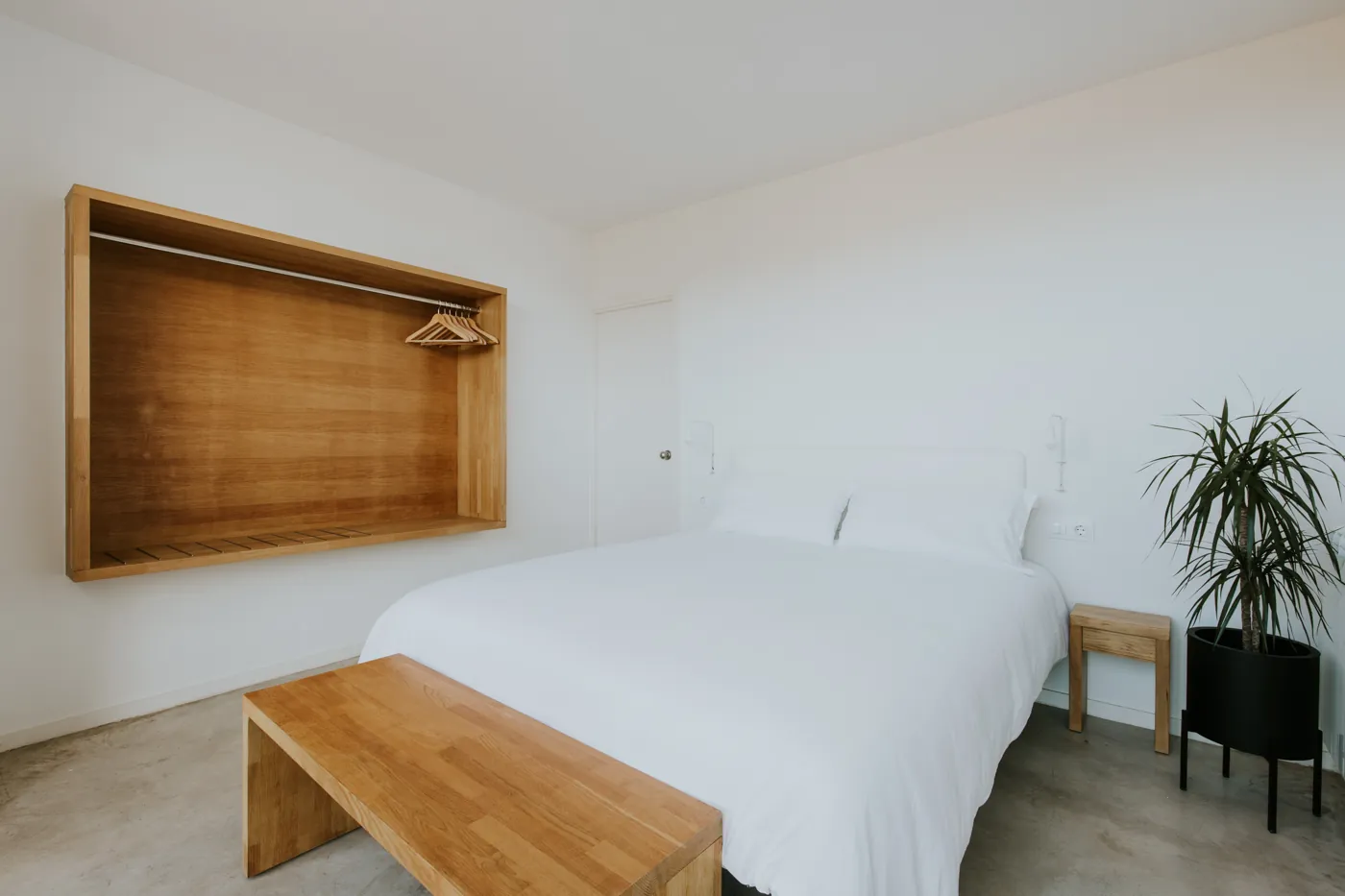 Habitación con cama de matrimonio, armario de roble y una planta junto a la ventana