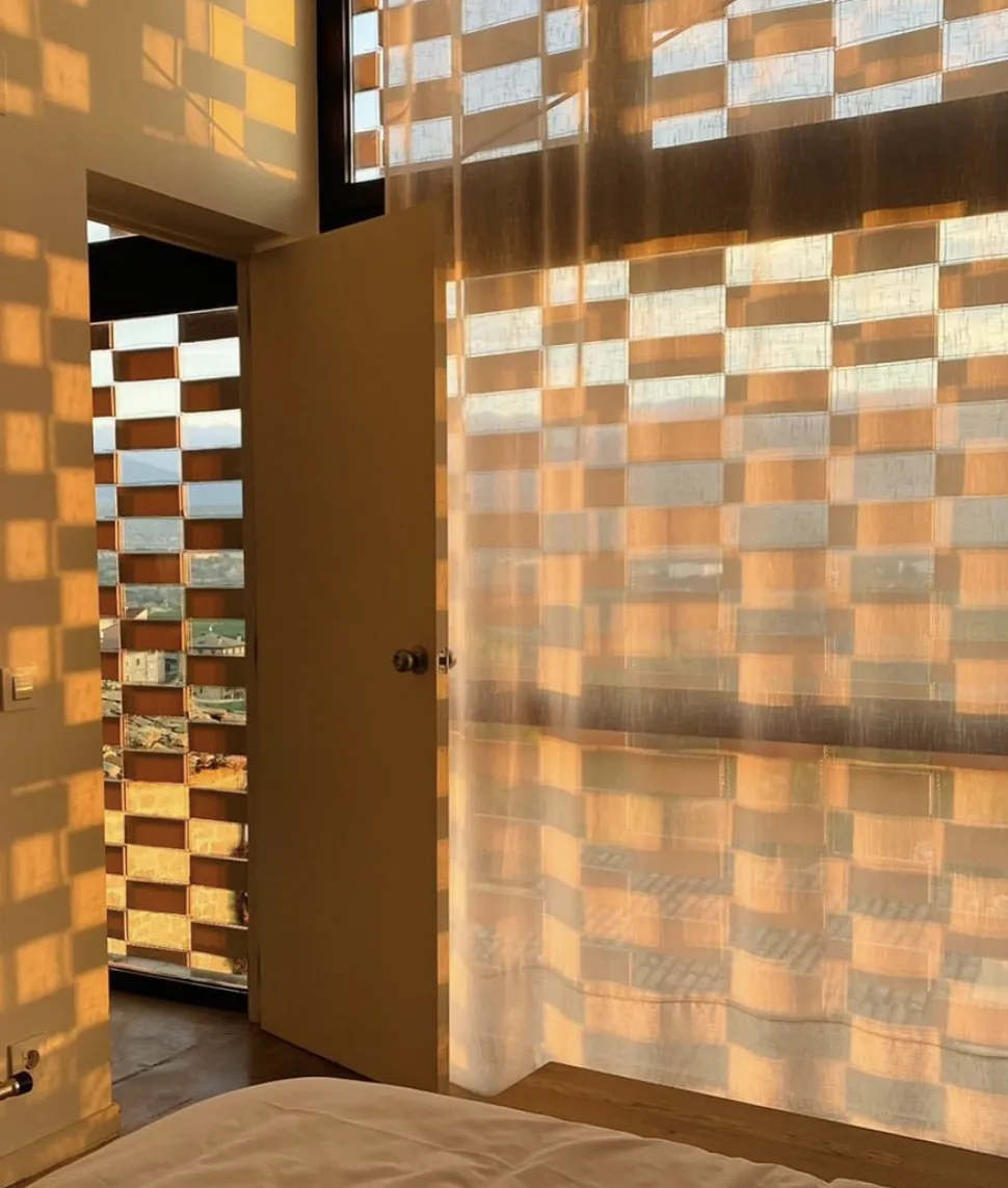 La luz del amanecer atraviesa la celosía y dibuja cuadros dorados en una habitación