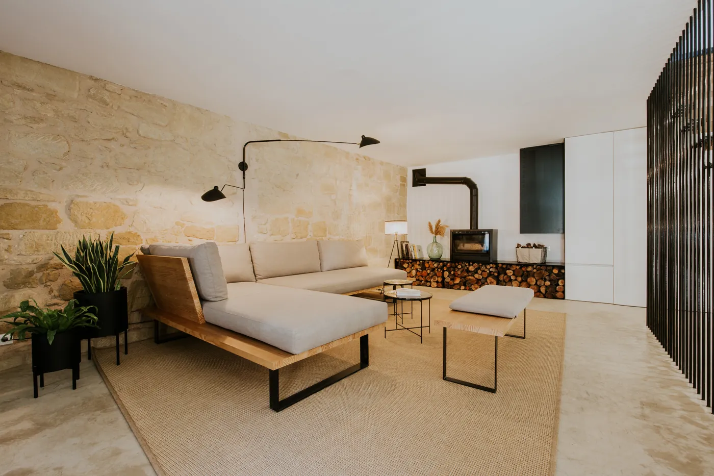 Salón de La Macana con sofá hecho a medida, pared de piedra y chimenea